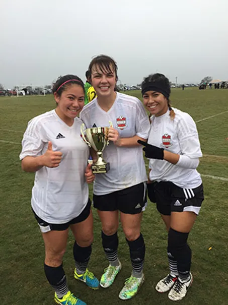 three girls with soccer trophy