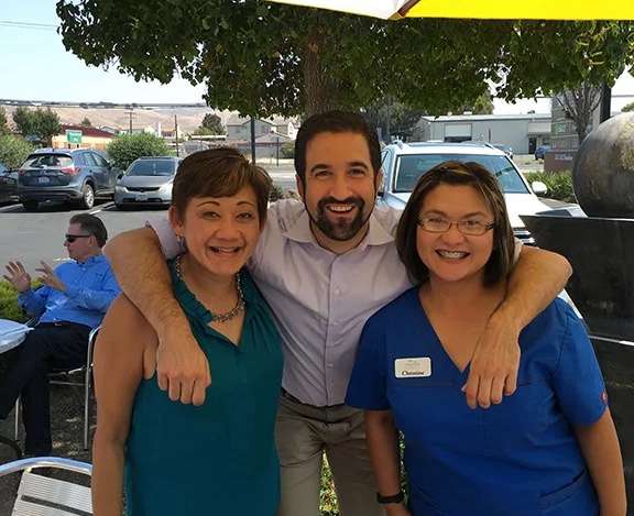 three people smiling, a man and two women