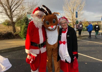 people smiling with reindeer (person in costume) and santa