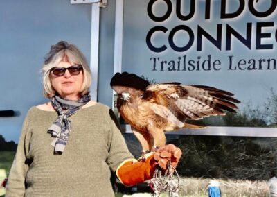 Wildlife Rescue volunteer with a red-tailed hawk in front of the Outdoor Connection mobile classroom