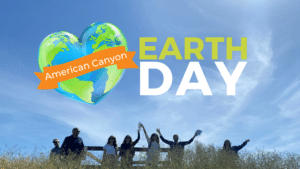 Earth Day image with people in grass and their hands up in celebration