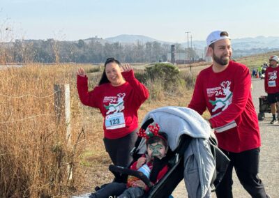 Family pushing a stroller waving while they run